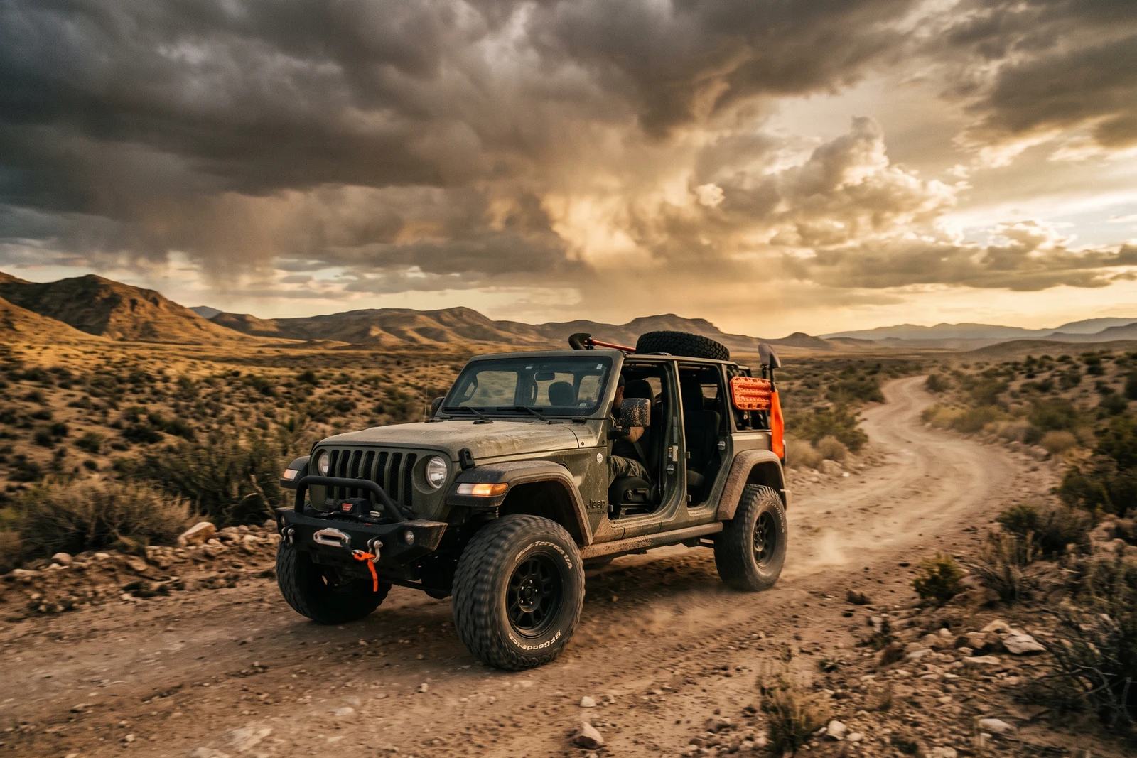 A Jeep Wrangler doors-off on an open desert road under a dramatic sky (building storm clouds or golden late-day light)